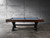 Side view lifestyle image of the Portland Slate Pool Table by Nixon Billiards, staged in a modern industrial game room with layered textures, natural lighting, and warm flooring. The rustic hardwood cradle runs the full length of the table, beautifully contrasting with the bold matte black X-style steel legs. This composition highlights the table’s architectural presence, balanced proportions, and premium materials. A clean, editorial-style shot that reflects the Portland’s dual role as both a high-performance slate billiards table and a design-driven furniture statement—exclusively curated by Sawyer Twain.

