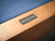 Detail shot of the Doc & Holliday steel logo plate embedded on the Paula Parsons Slate Pool Table, symbolizing handcrafted American quality and luxury design.