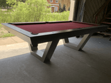 The Matrix Pool Table placed near a hotel pool deck with sun chairs and umbrellas, designed for all-weather use with sleek modern styling and outdoor-grade felt.